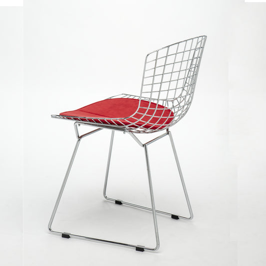 Modern Bertoia wire side chair with a polished chrome steel frame and red upholstered seat cushion on a white background.
