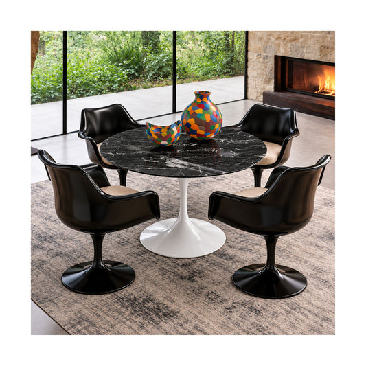 Round black marble Saarinen Tulip dining table paired with four black Tulip armchairs featuring upholstered seat cushions and sculptural pedestal bases in a luxury contemporary dining room with a fireplace.