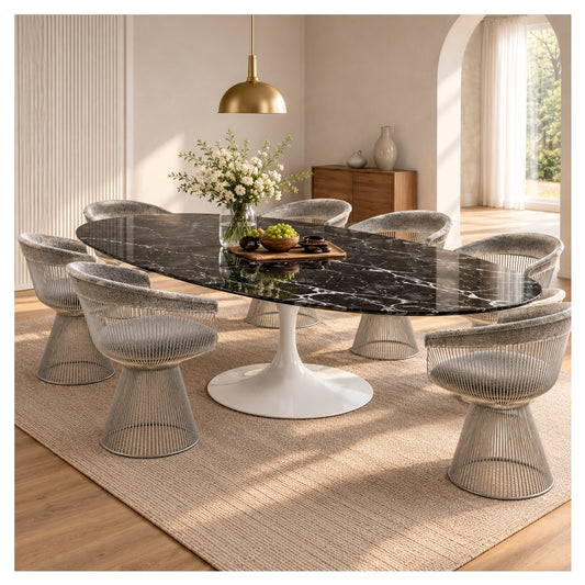 Large oval Tulip executive table with a black veined ceramic top and white pedestal base, surrounded by silver wire chairs in a bright room.
