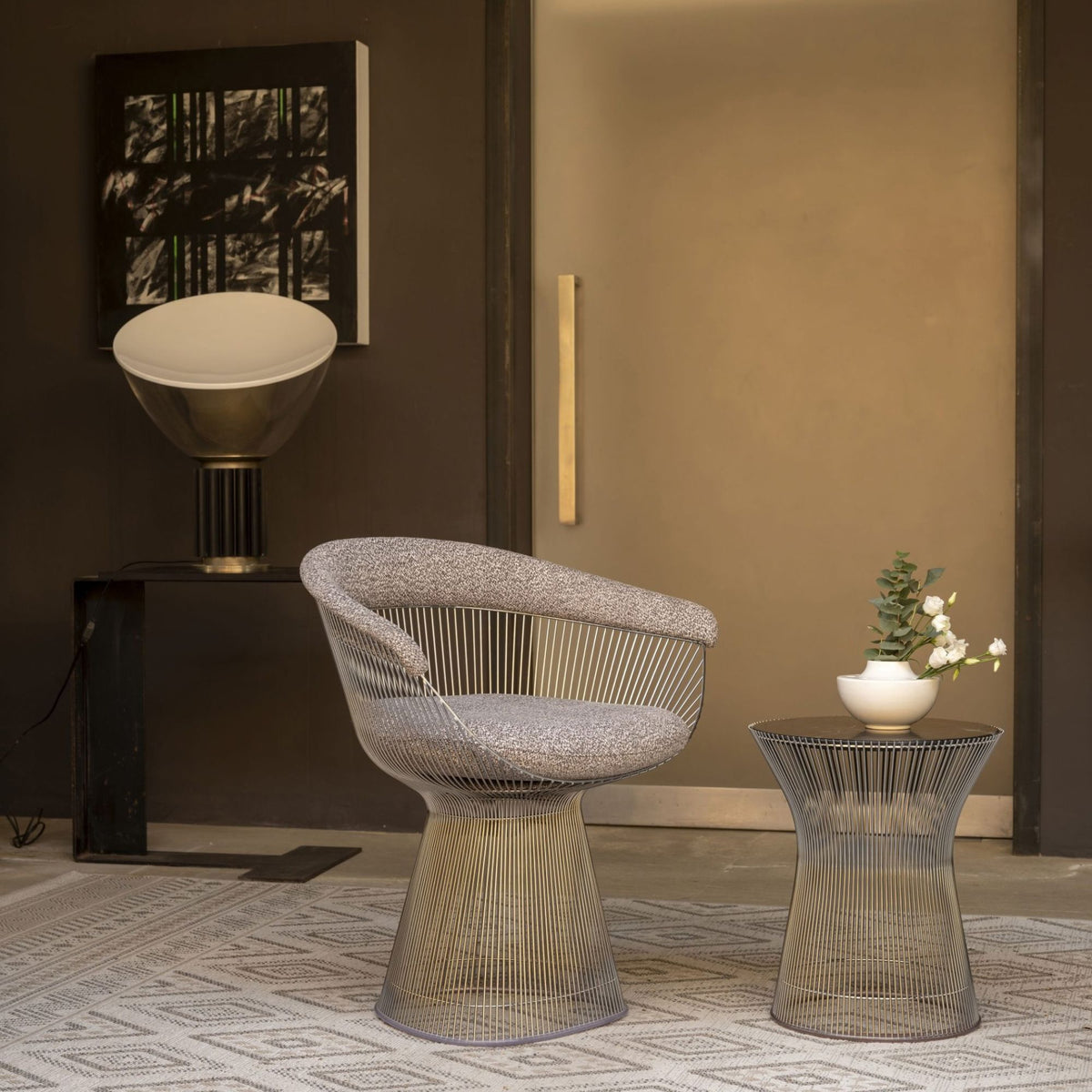 Modern Platner wire lounge chair with grey upholstered cushions paired with a matching wire side table, featuring sculptural stainless steel rod construction in a contemporary luxury interior