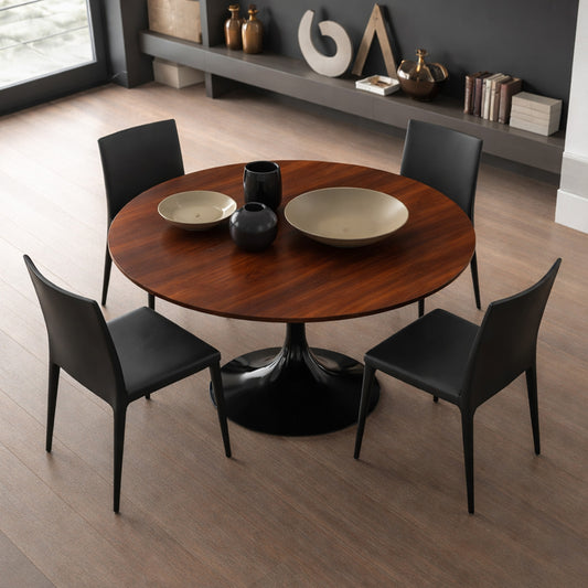 Round tulip dining table with walnut wood top and black pedestal base, styled with four black chairs in a modern dining room