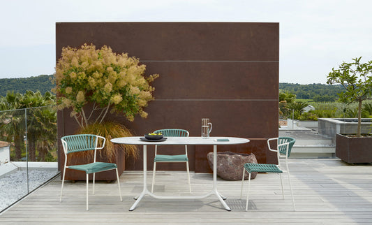 S•CAB Tripé Double Dining Table Base with an oval tabletop paired with Lisa Filò chairs in a contemporary outdoor dining setting.