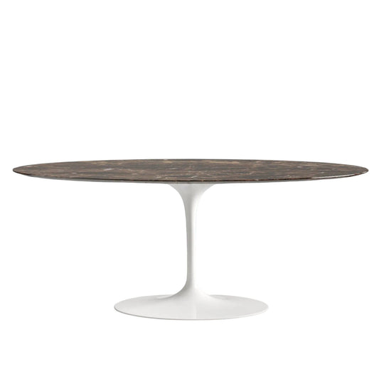 Oval dining table with a marble emperador top and white base on a white background