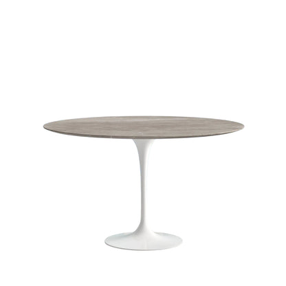 Round dining table with a wooden top and white base on a white background