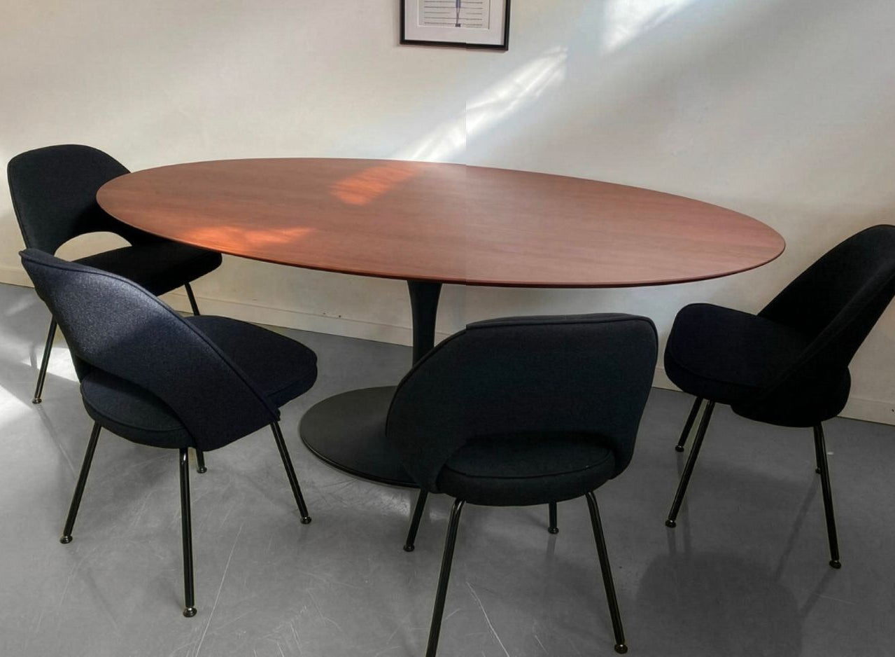 Round wooden table with four black chairs in a room.
