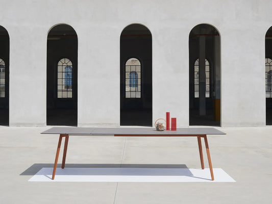 SCAB Squid outdoor extendable table with slim HPL top and terracotta aluminium legs, displayed in a contemporary architectural courtyard to showcase its Italian minimalist design.