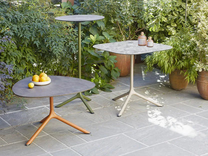SCAB Tripè round outdoor bistro table with an olive green powder-coated aluminium base, paired with a lounge armchair in a contemporary garden patio setting, ideal for cafés, hotels and residential terraces.