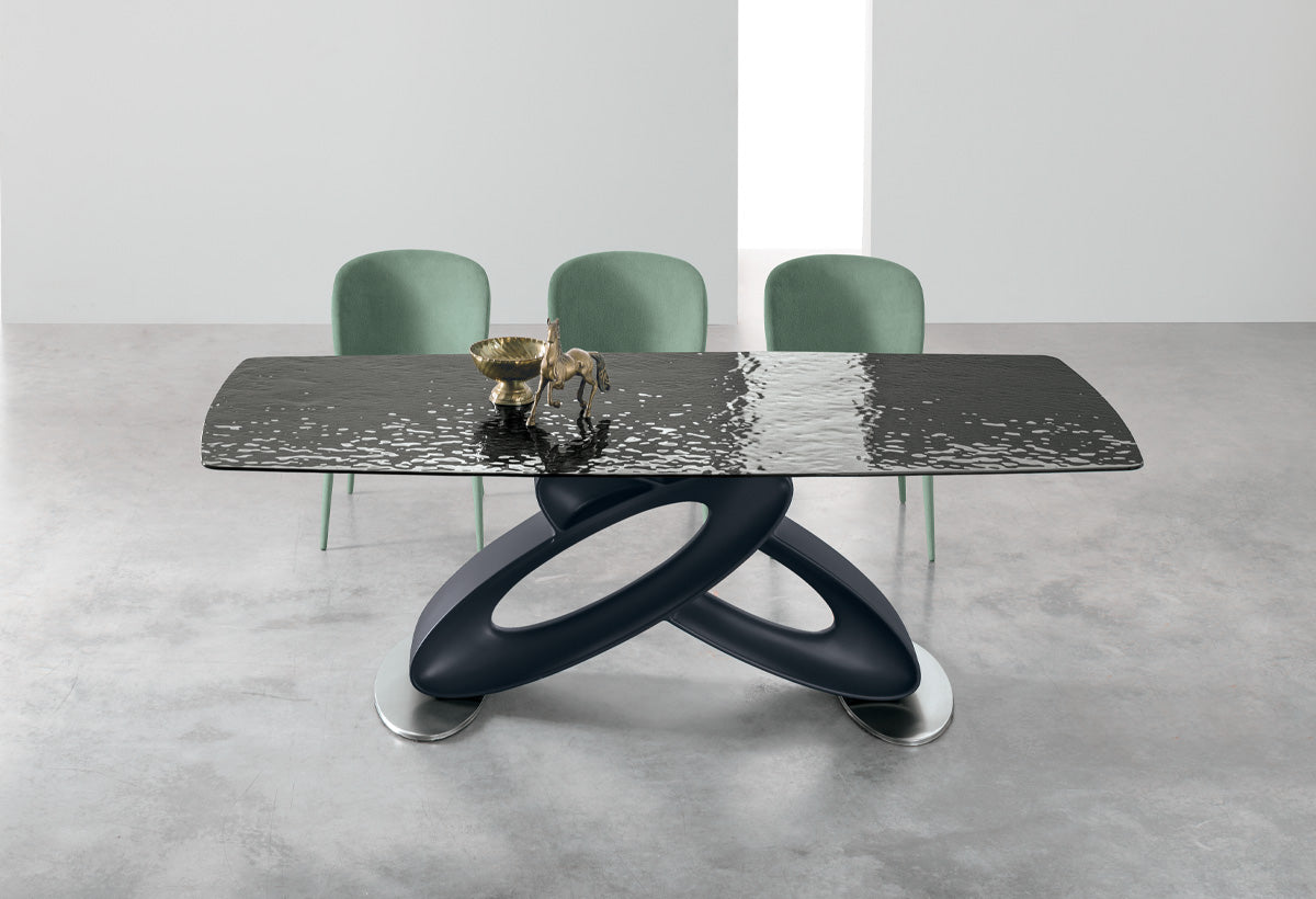 Front view of the Target Point Eclipse Fixed Dining Table featuring a black sculptural base and black textured Dunes glass barrel-shaped tabletop with modern dining chairs.