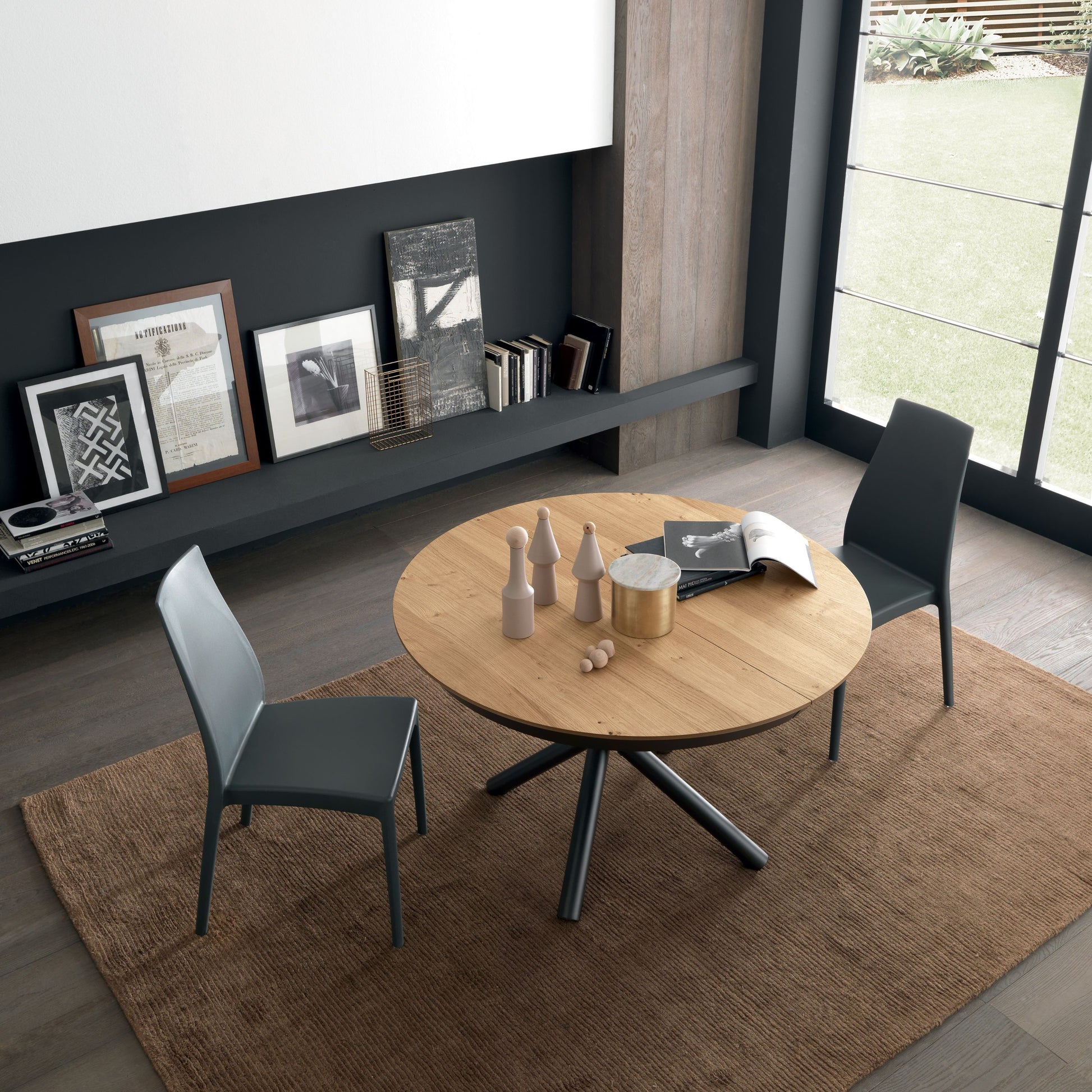 Modern dining area with round wooden table and chairs in a stylish room.