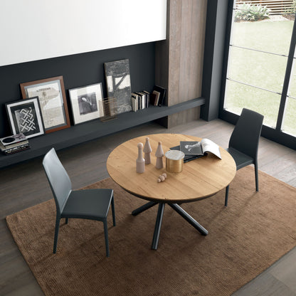 Modern dining area with round wooden table and chairs in a stylish room.