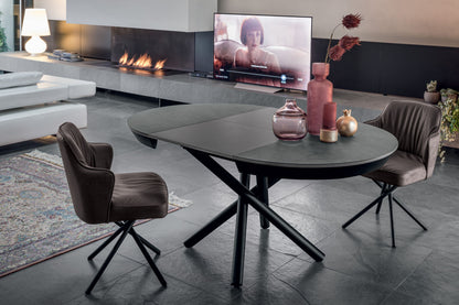 Modern living room with a round table, chairs, and a TV displaying a woman.