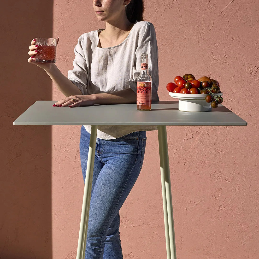 Close-up of the S•CAB Atomo Bistro Table Base with a square bar-height tabletop in a contemporary outdoor hospitality setting.