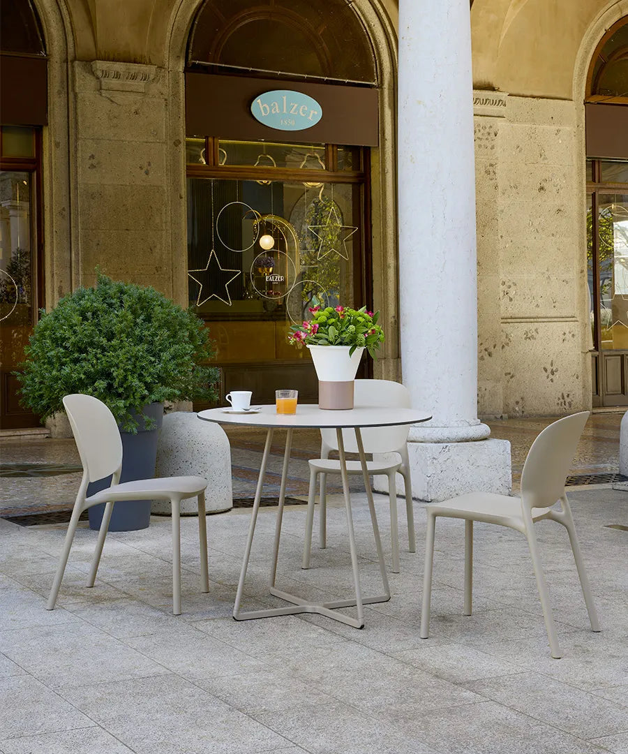 S•CAB Atomo Bistro Table Base with a round tabletop paired with matching chairs in a stylish outdoor café setting.