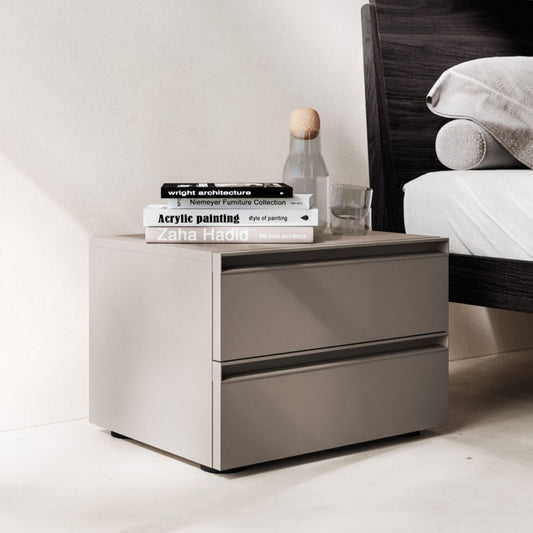 Modern nightstand with books and a bottle next to a bed with white bedding.