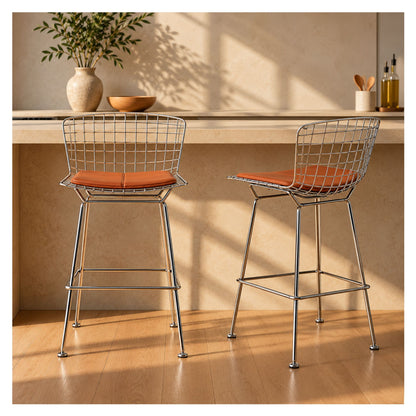 Pair of Bertoia-inspired chrome wire counter stools with tan cushions beside a kitchen island