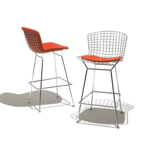 Pair of Bertoia wire counter stools with polished chrome frames and red upholstered seat pads on a white background.