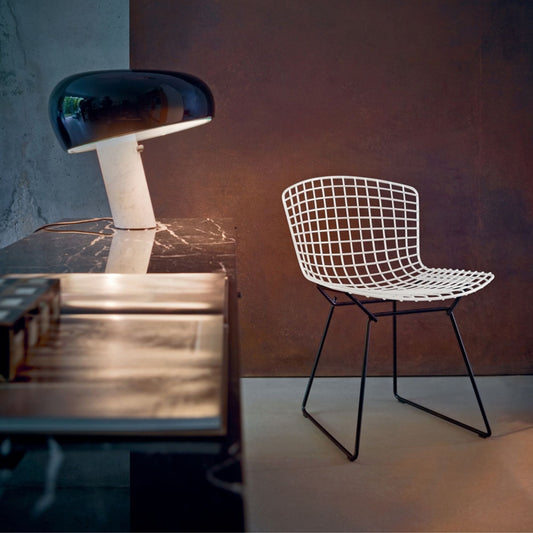 Harry Bertoia inspired wire side chair with a white welded steel grid shell and black sled base, styled in a contemporary interior, combining iconic mid-century modern design with sculptural elegance for dining rooms, offices and hospitality spaces.