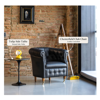 Black Chesterfield club chair paired with a black Tulip round side table in an industrial-style living room featuring exposed brick walls, a leather armchair, and a modern accent lamp.