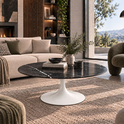 Black marble-effect oval Tulip coffee table with a white pedestal base styled in a luxury modern living room with contemporary décor and natural daylight.