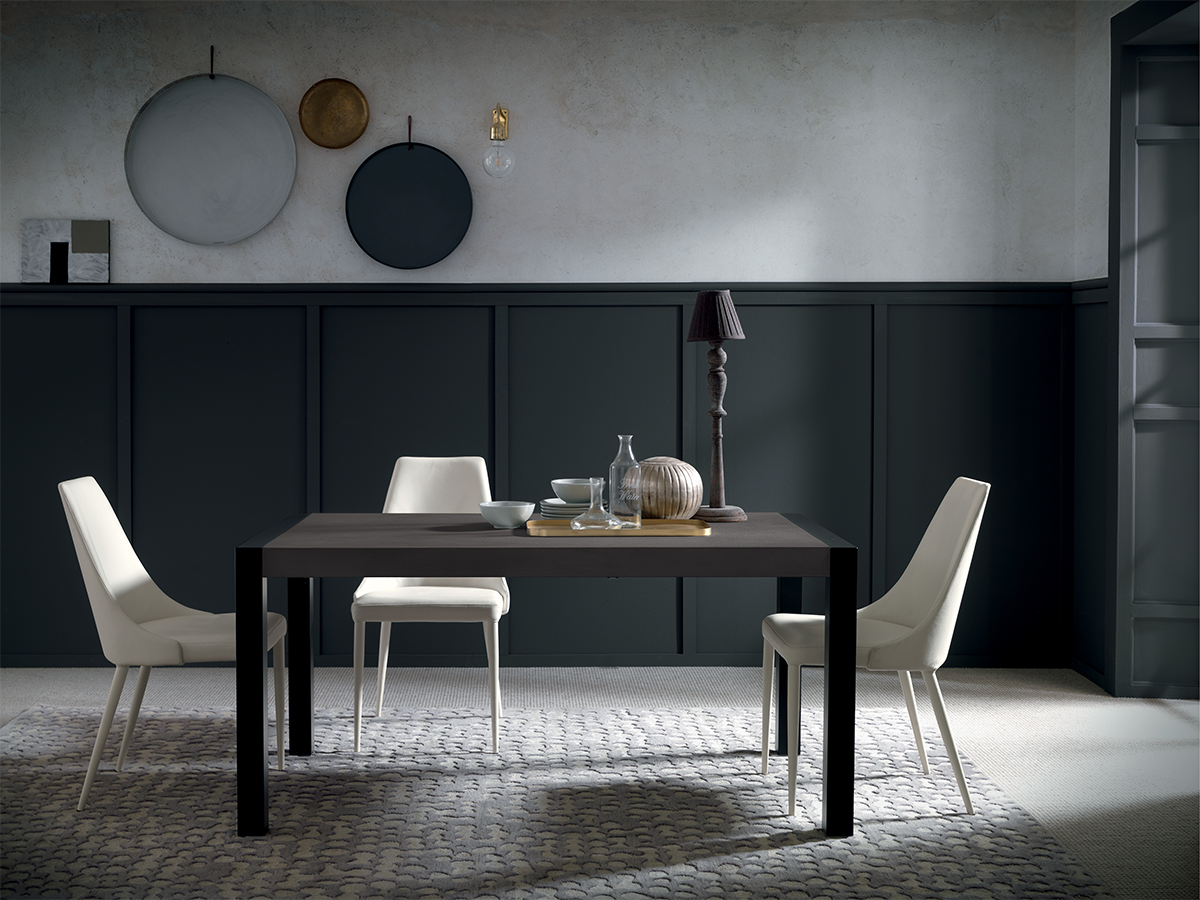 Black rectangular dining table styled in modern luxury dining room with soft lighting