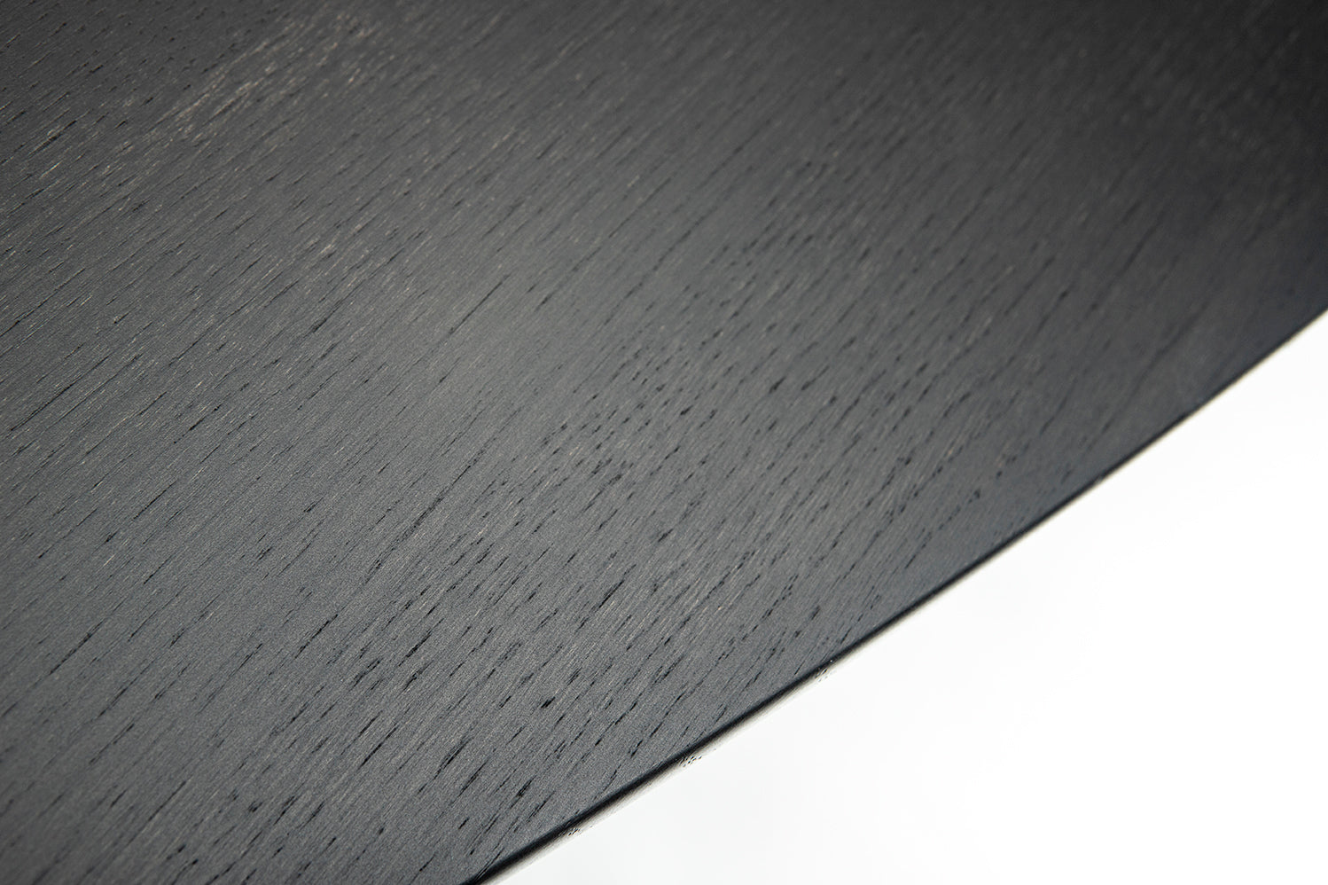 Close-up detail of black wood tulip dining table edge showing natural grain texture and curved profile