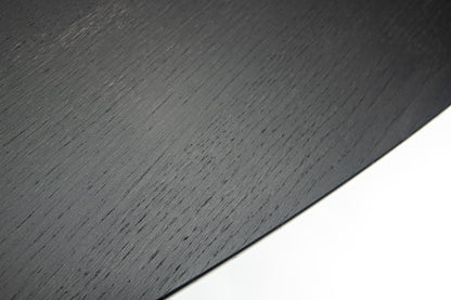 Close-up detail of black wood tulip dining table edge showing natural grain texture and curved profile