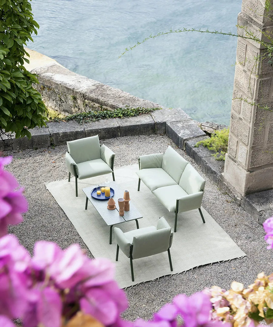 S•CAB Brezza outdoor lounge set with sofa, armchairs, and coffee table arranged on a terrace overlooking the water.