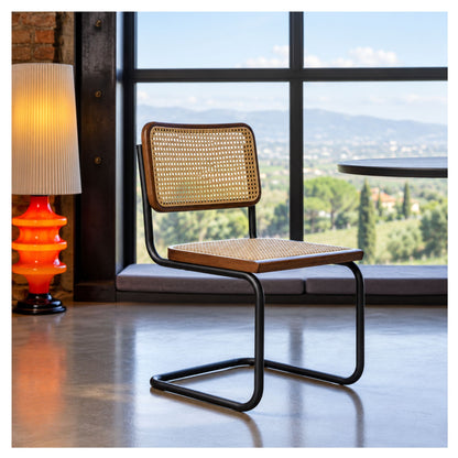 Natural cane dining chair with a black cantilever frame beside a large window