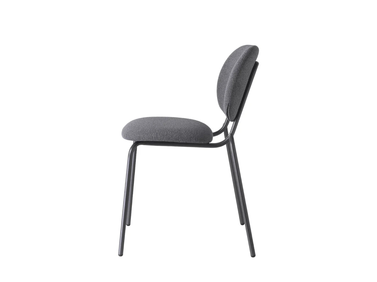 Side view of a charcoal upholstered dining chair with a rounded backrest, padded seat, and slim dark metal frame.