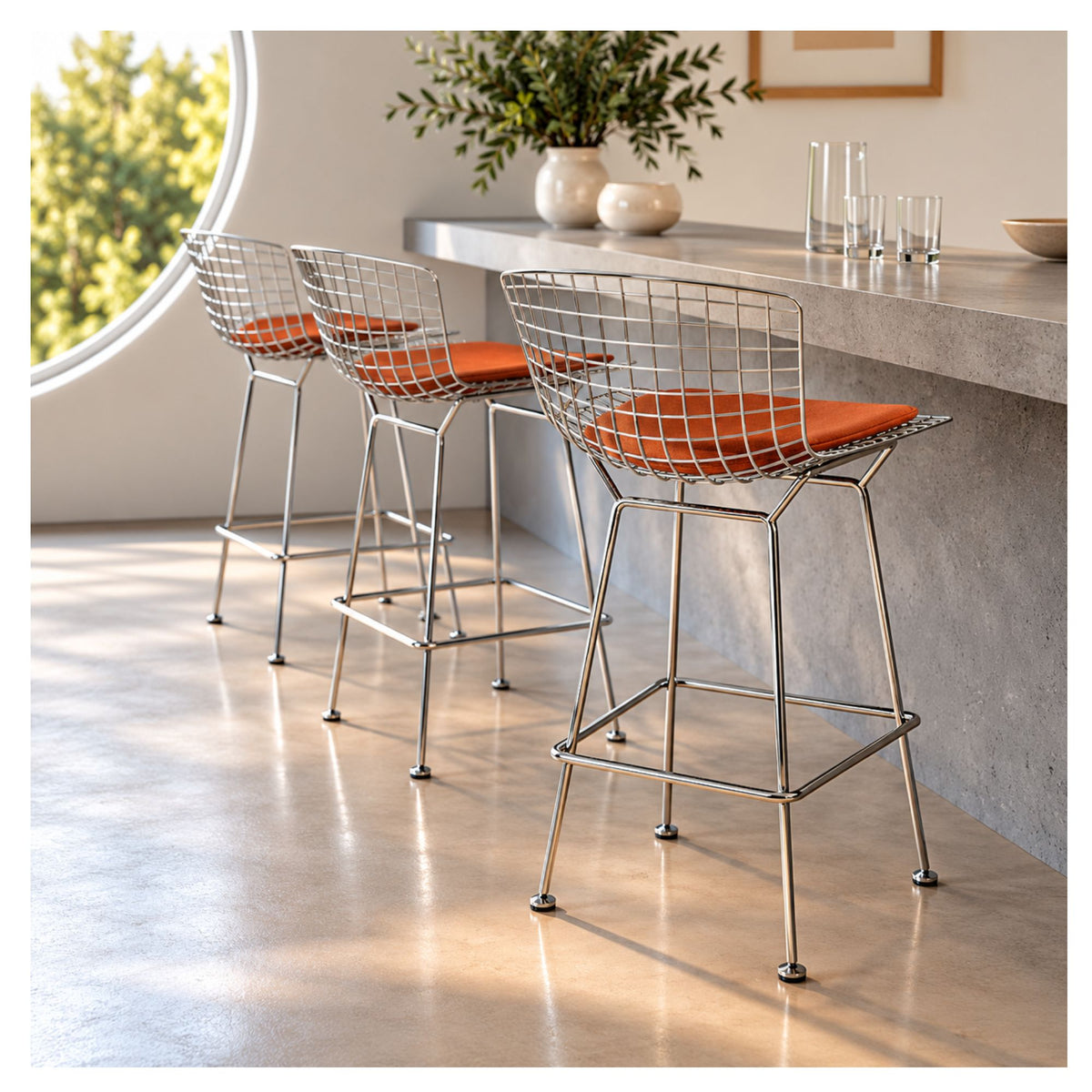 Chrome wire counter stools with upholstered cushions arranged at a modern kitchen island