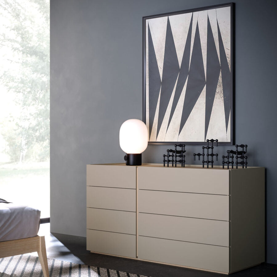 Beige dresser with a lamp and decorative items against a gray wall with a geometric art piece.