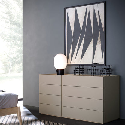 Beige dresser with a lamp and decorative items against a gray wall with a geometric art piece.