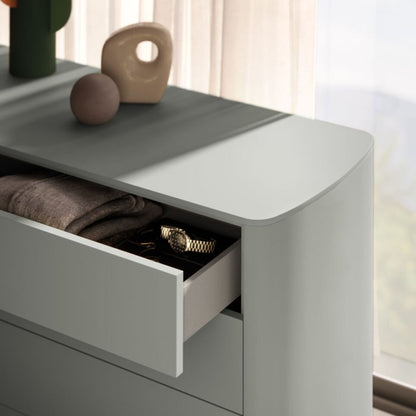Modern gray dresser with open drawer containing folded clothes and decorative items on top.
