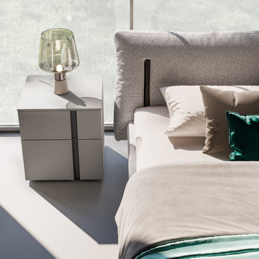 Modern bedroom with a bed and nightstand featuring a lamp.