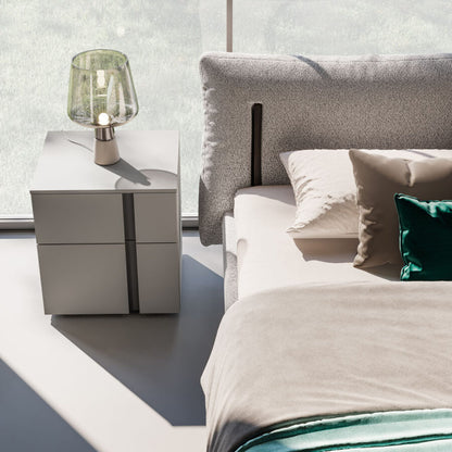 Modern bedroom with a bed and nightstand featuring a lamp.