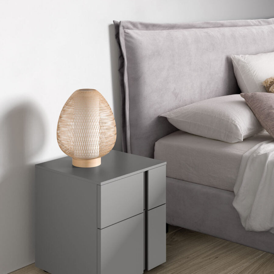 Gray nightstand with a textured table lamp next to a bed with gray bedding.