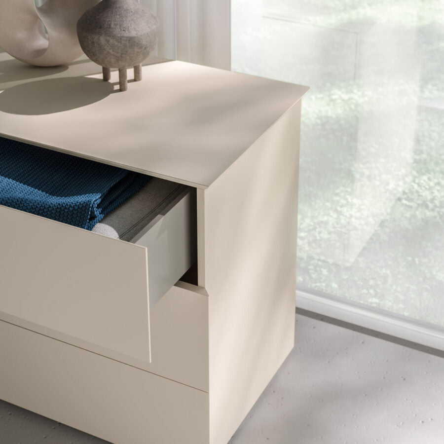 Beige drawer with open drawer revealing blue fabric, against a light background.