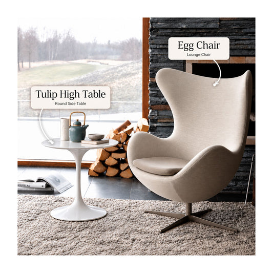 Cream Egg lounge chair paired with a white Tulip high side table featuring a round pedestal base in a contemporary living room with a stone fireplace and floor-to-ceiling window.