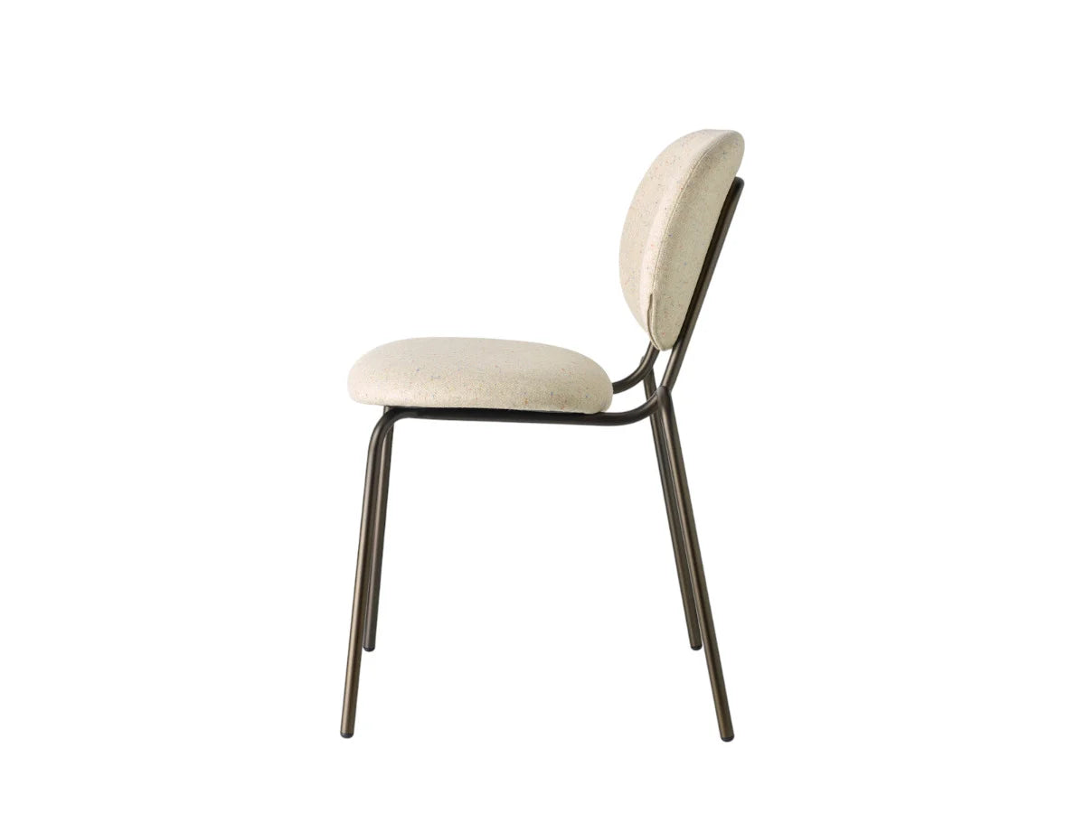 Side view of a cream upholstered dining chair with a rounded backrest, padded seat, and slim dark metal frame.