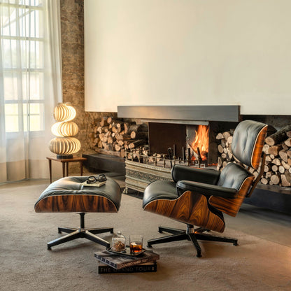 CTS Design Eames-style lounge chair and matching pouf with brown upholstery and a curved wood shell in a living room