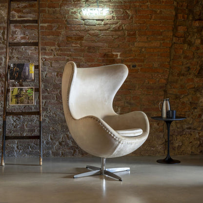 Cream velvet Egg Chair with a polished aluminium swivel base, featuring a sculptural high-back wing design for modern living rooms, hotel lounges, executive offices and luxury contemporary interiors.