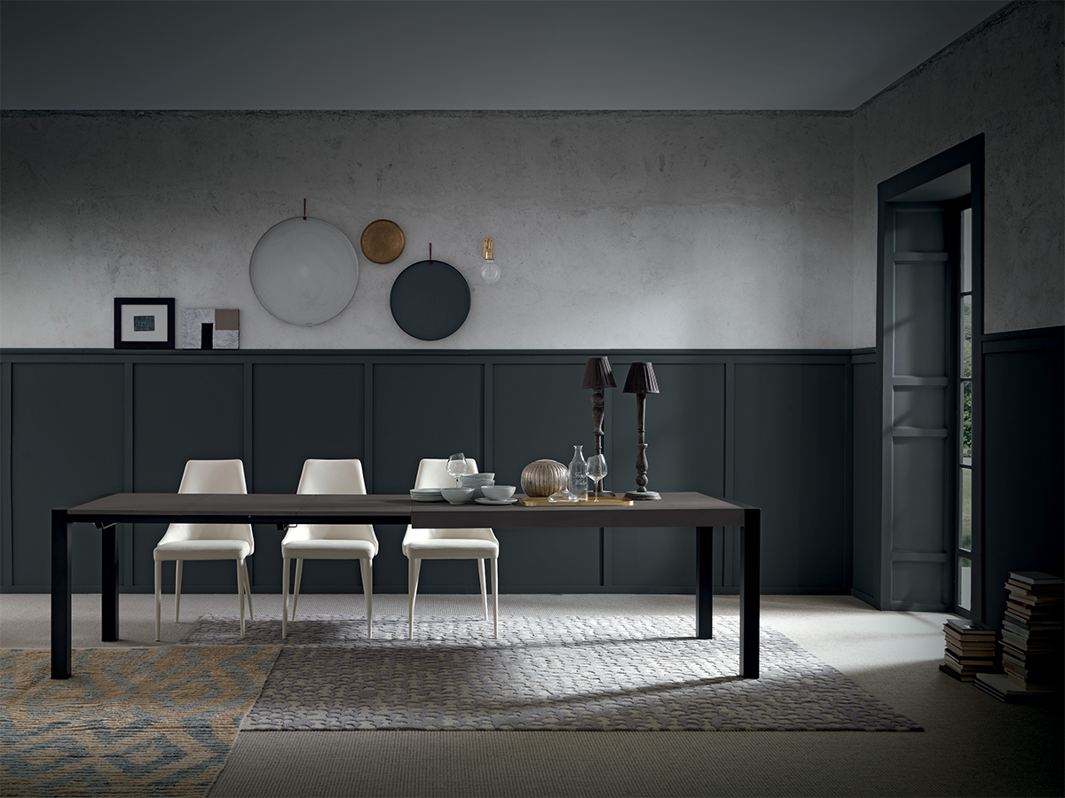 Extendable black dining table in modern minimalist room with white chairs