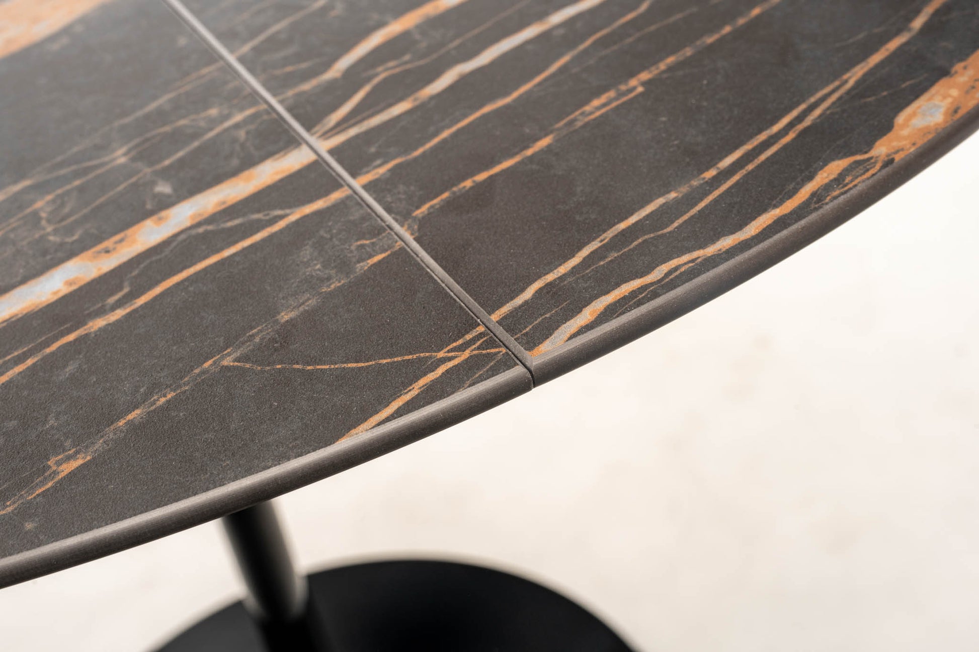 Close-up detail of extendable tulip dining table with Noir Desir ceramic top and gold veining showing extension joint and edge thickness