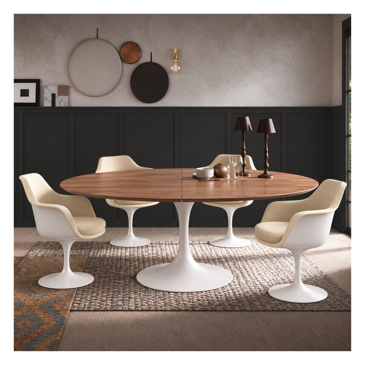 Extendable oval Tulip dining table with a warm oak top and white pedestal base, surrounded by white chairs with beige seats.