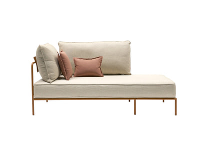 Flap 2902 outdoor daybed with cream upholstered cushions, left armrest, and slim bronze metal frame with accent pillows.