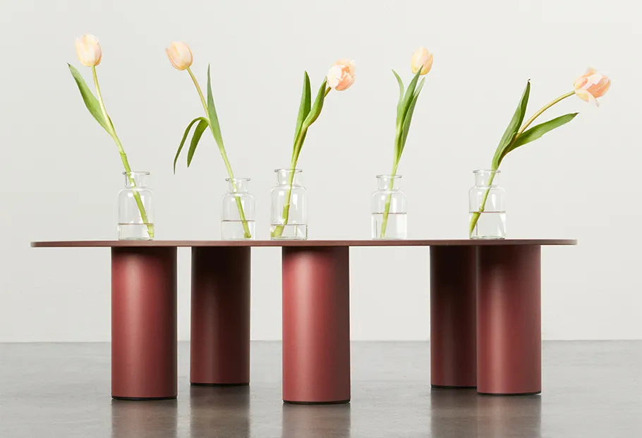 S•CAB Hyppo Outdoor Coffee Table L 104 cm in a terracotta finish styled with glass vases and tulips in a contemporary interior setting.