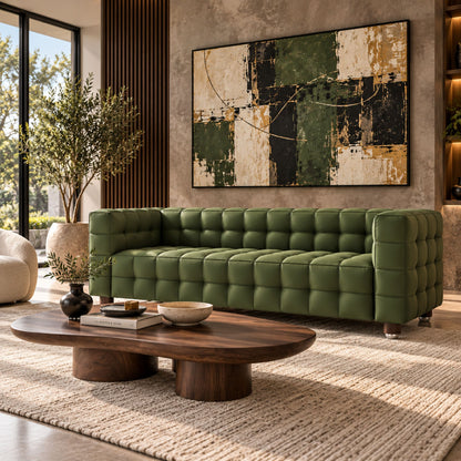 Isamu Noguchi coffee table with an organic glass top and sculptural walnut wood base, styled in front of a green leather Josef Hoffmann Kubus sofa featuring iconic cube-tufted upholstery in a contemporary luxury living room.