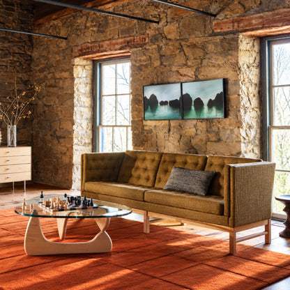 Isamu Noguchi glass coffee table with a sculptural solid wood base and organically shaped glass top, styled in a rustic modern living room with a tufted sofa, chess set, and warm natural lighting, showcasing an iconic mid-century modern designer coffee table