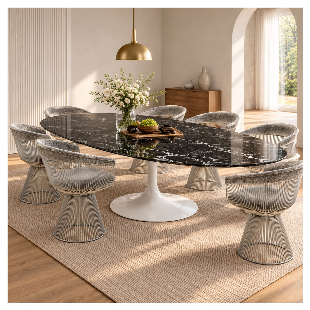 Large oval Tulip executive table with a black veined ceramic top and white pedestal base, surrounded by silver wire chairs in a bright room.