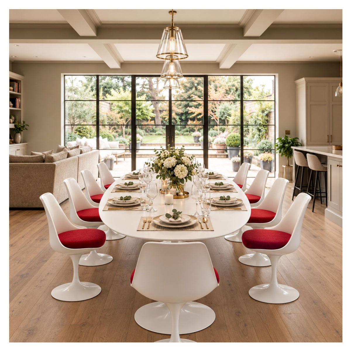 Large oval Tulip executive table with a white top and pedestal base, set for dinner and surrounded by white chairs with red seat cushions.